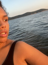 a woman in a black bikini posing in front of a body of water